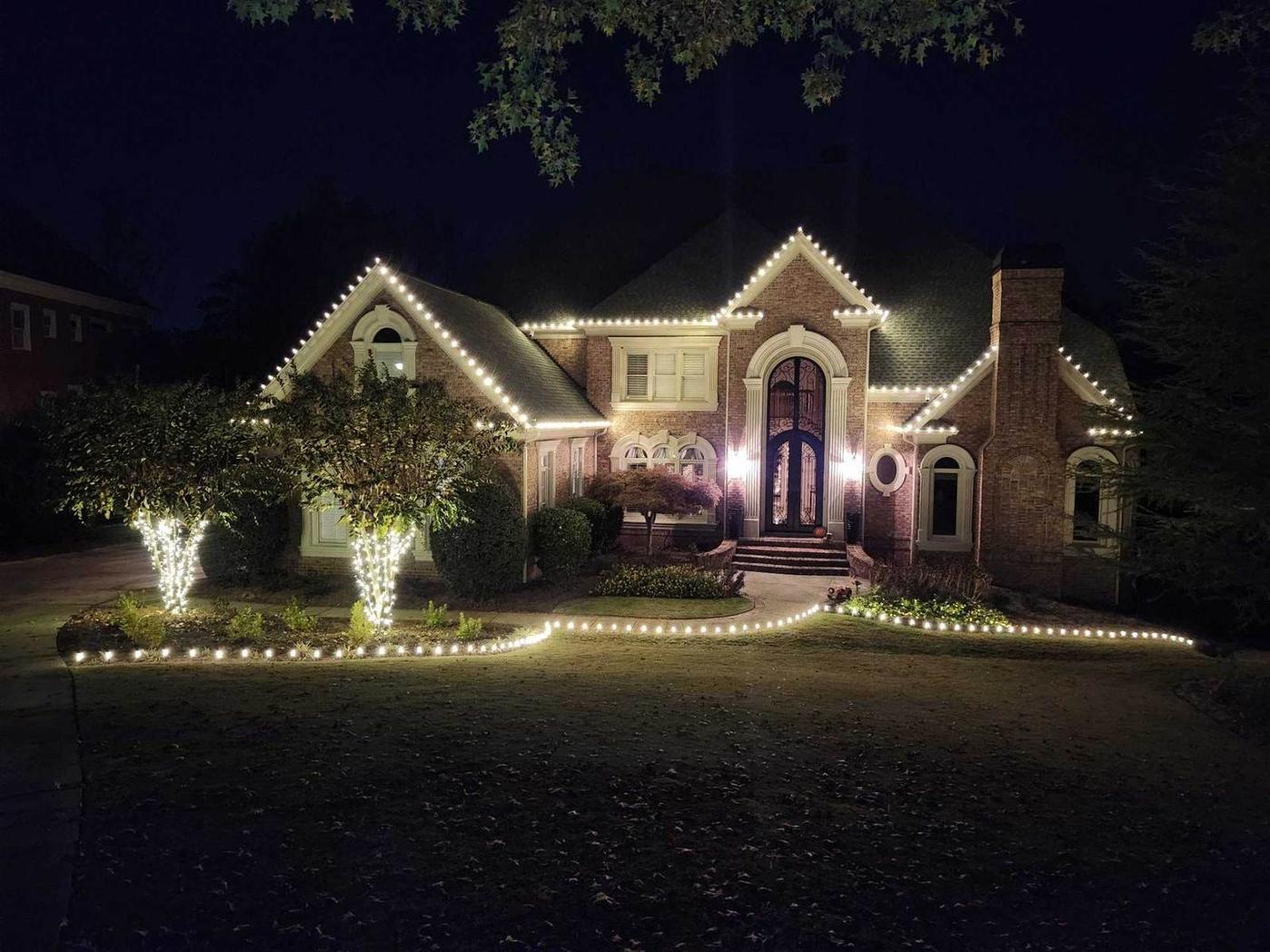 Luxury brick home Christmas light installation in Atlanta with lit landscape trees