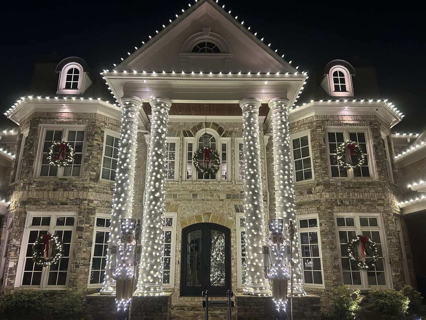 Luxury Atlanta estate wrapped in warm white Christmas lights with nutcrackers and wreaths