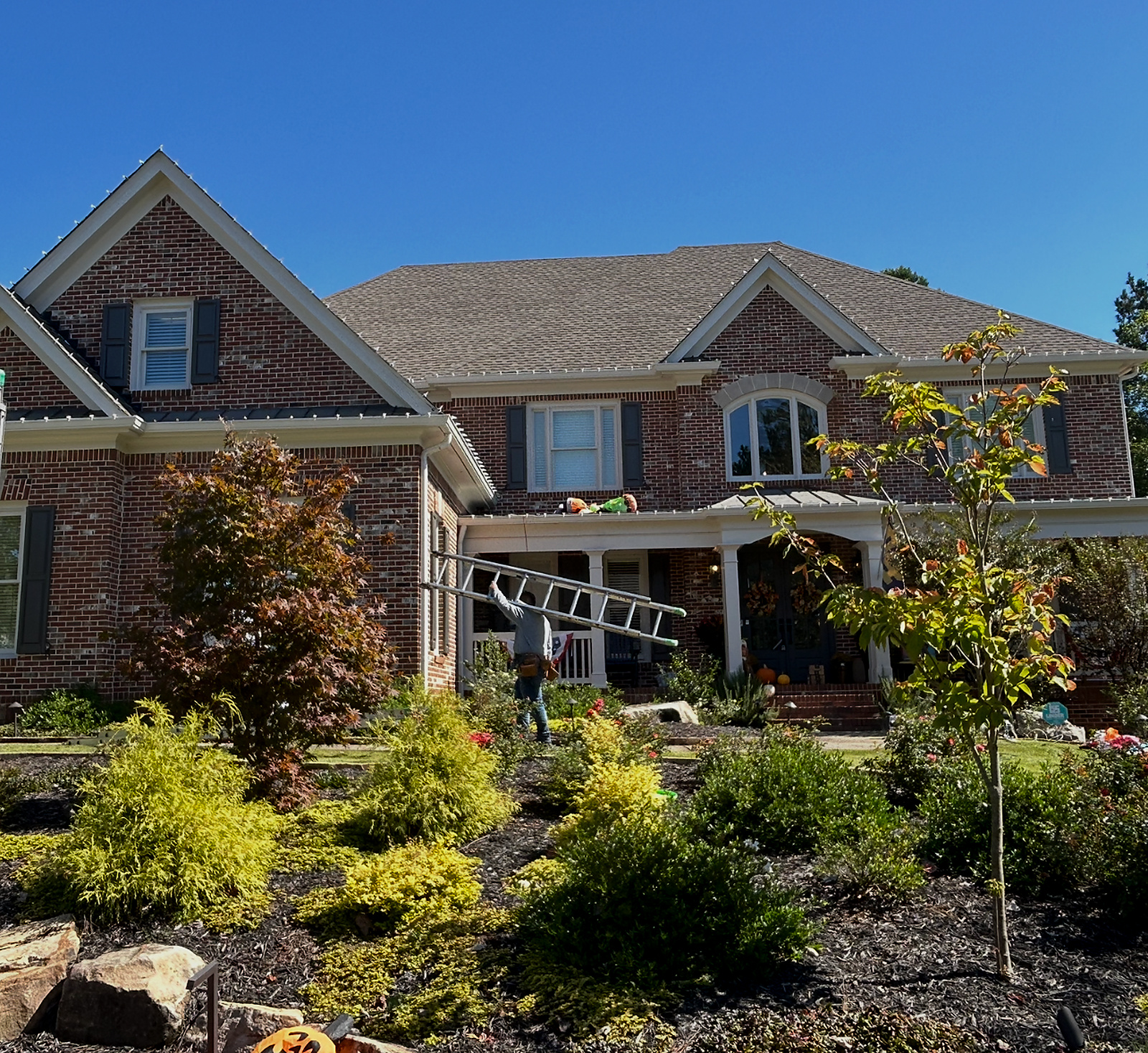 Professional Christmas light installers working on a brick home in Atlanta