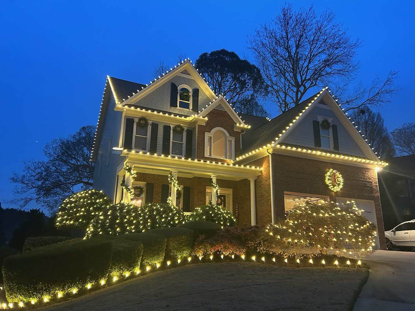 Luxury estate Christmas light installation in Buckhead GA with warm white C9 roofline and lit bushes