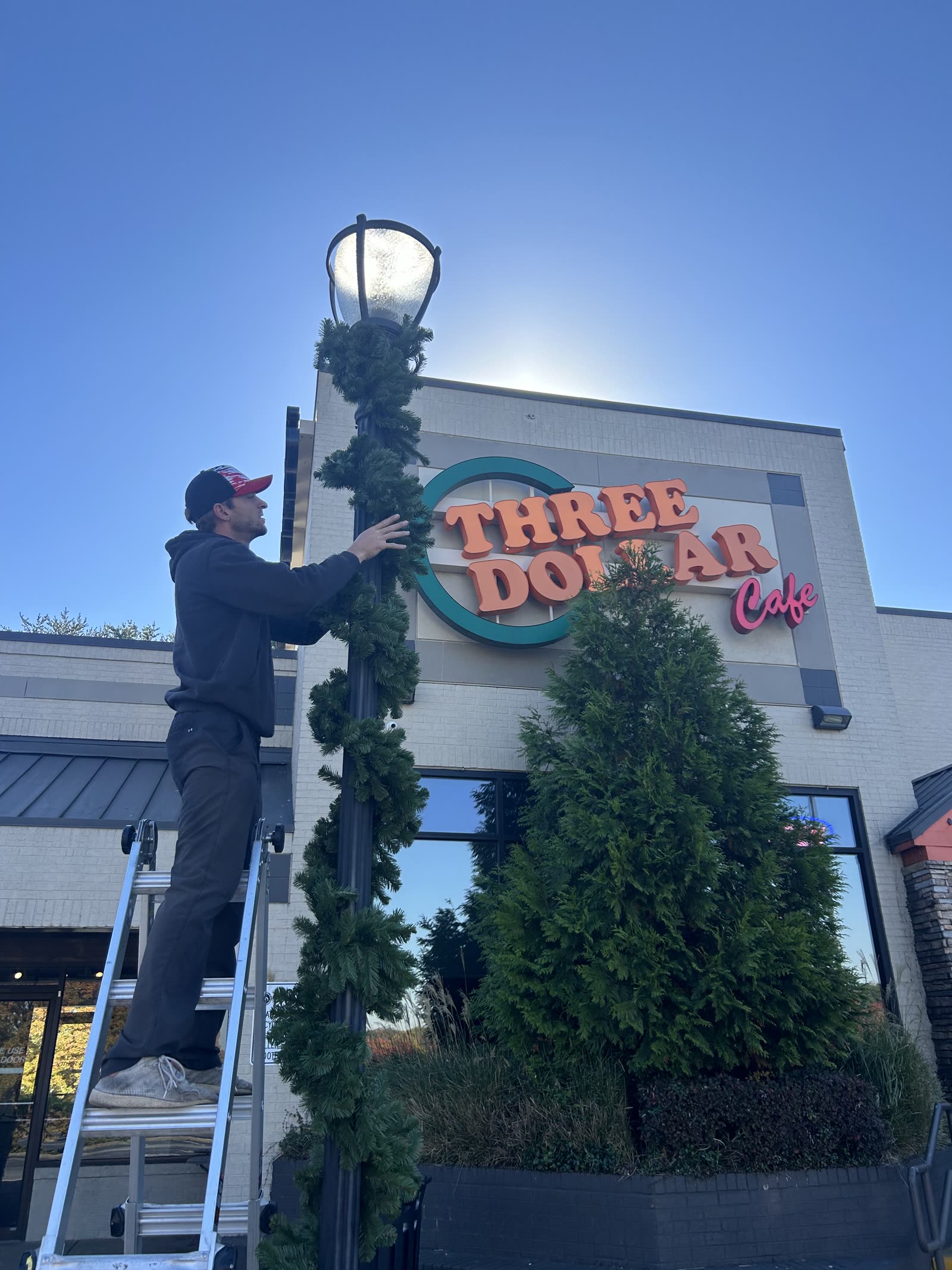 Dreamland installer wrapping garland on a storefront lamp post in metro Atlanta
