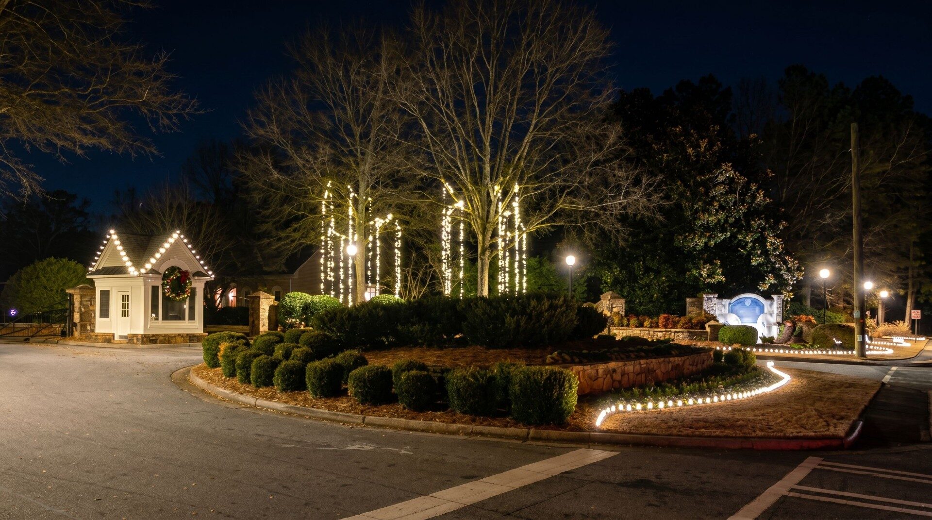 HOA gatehouse with Christmas lights and lit tree canopy in metro Atlanta community